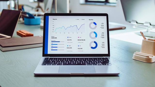 Laptop with IT monitoring dashboard on desk - symbolic image for successful implementation, individual customization and fast ROI by USU Services.