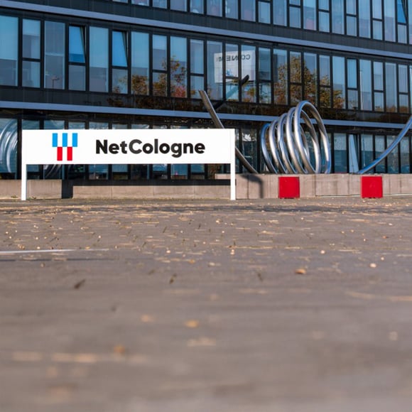 Exterior view of the NetCologne building with logo and modern architecture, a customer of the USU IT monitoring solution.