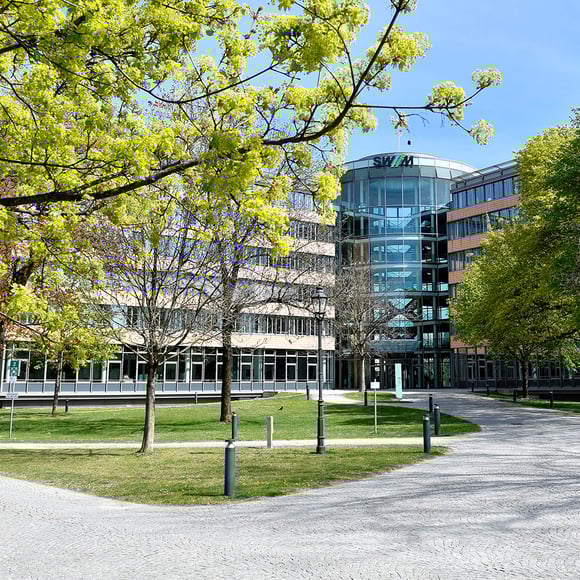 Exterior view of the Stadtwerke München (SWM) building, surrounded by green nature. SWM is a customer of the USU IT monitoring solution.